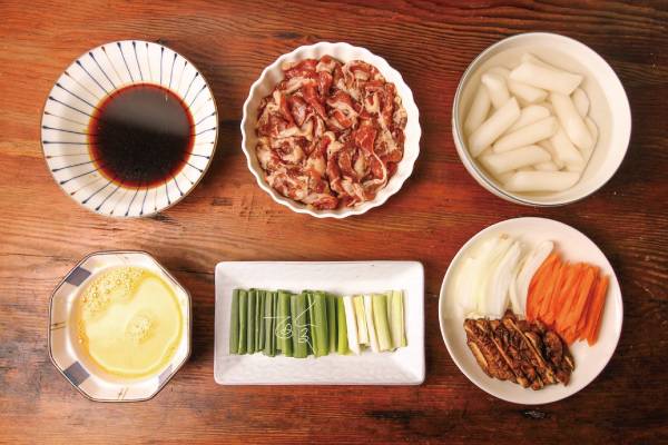 1. 蔥切段；洋蔥切半⽉形；紅蘿蔔切絲；乾香菇⽤⽔泡開後切絲；蛋打散；年糕⽤熱 ⽔泡軟；牛肉片切成一口大⼩，⽤醃料醃製⼗分鐘。